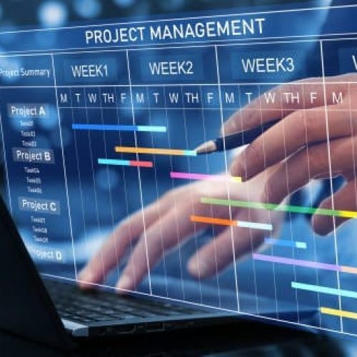 Project manager working on laptop and updating tasks and milestones progress planning with Gantt chart scheduling interface for company on virtual screen. Business Project Management System